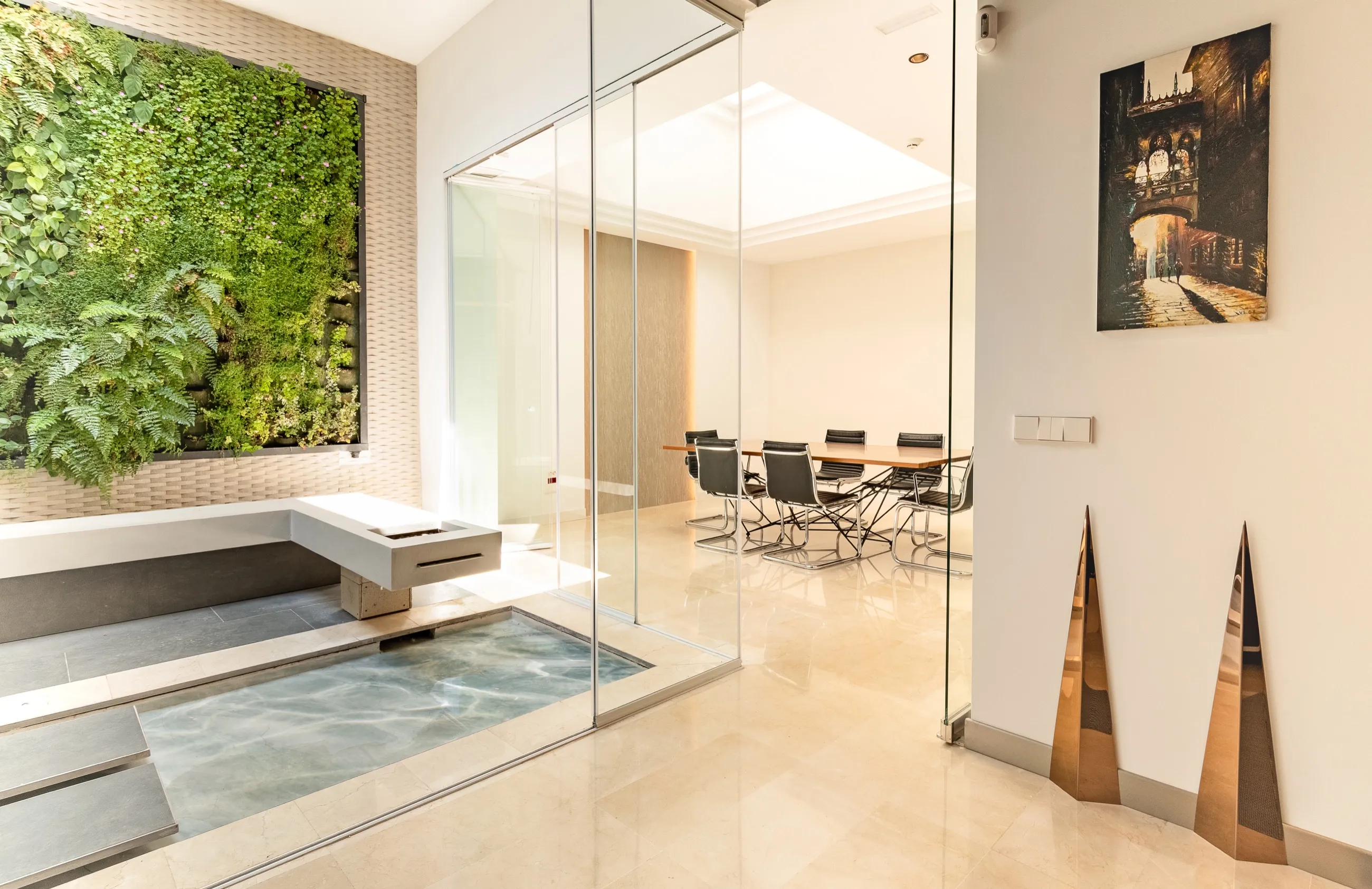 Sala de reuniones acristalada de AB Estudio en Palma, junto a un jardín vertical y una lámina de agua
