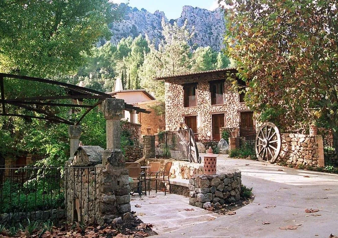 Entrada al hotel Es Ratxó en Puigpunyent con edificio de piedra y rueda de molino