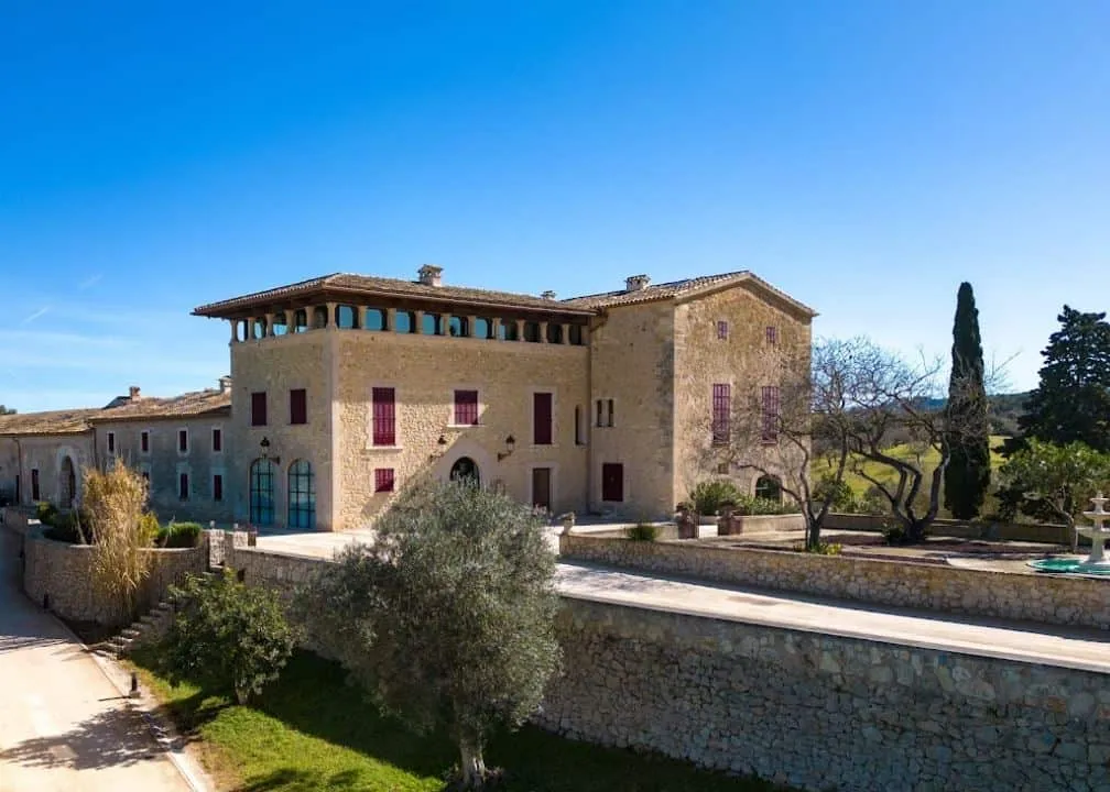 Fachada de piedra del hotel Finca Sa Bastida en Sant Joan, Mallorca, con tejado de teja y olivos