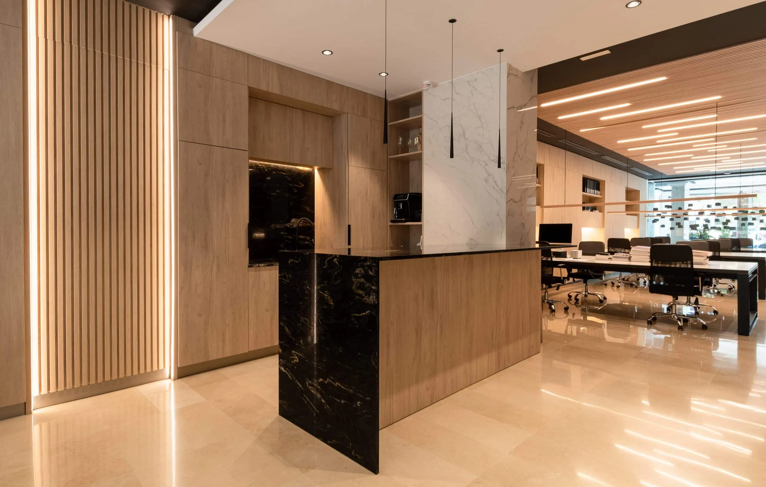 Barra de recepción con piedra negra y paneles de madera en la oficina HOMEY de Palma