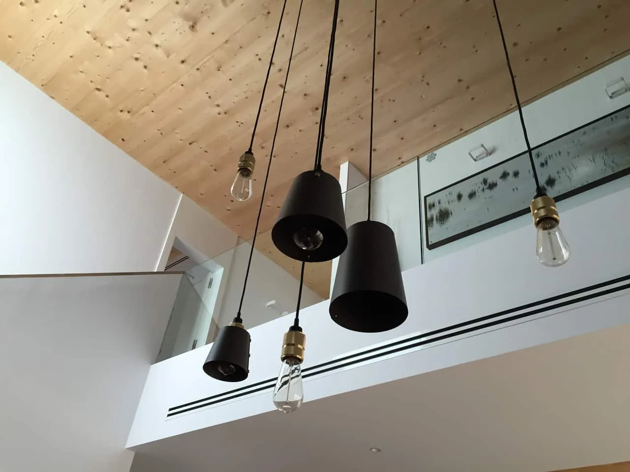 Interior de doble altura de ADG con techo de madera y lámparas colgantes