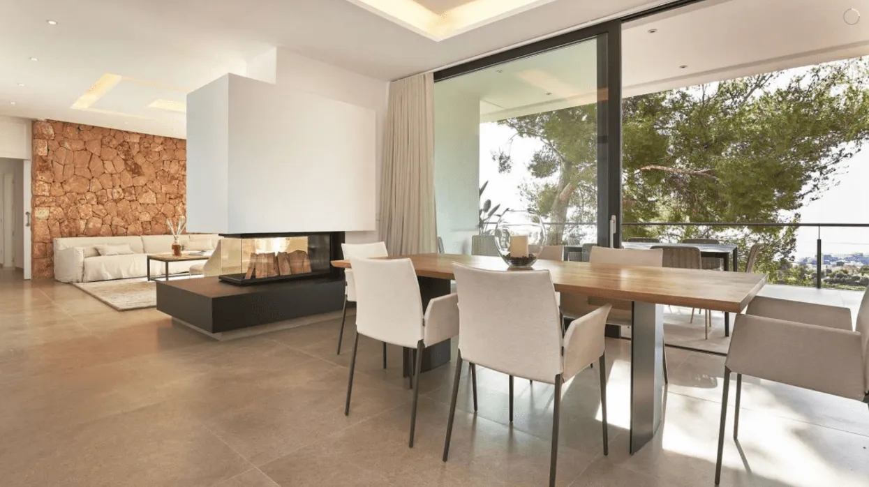 Comedor y salón de la vivienda Génova, Palma, con mesa de madera y vistas al pinar