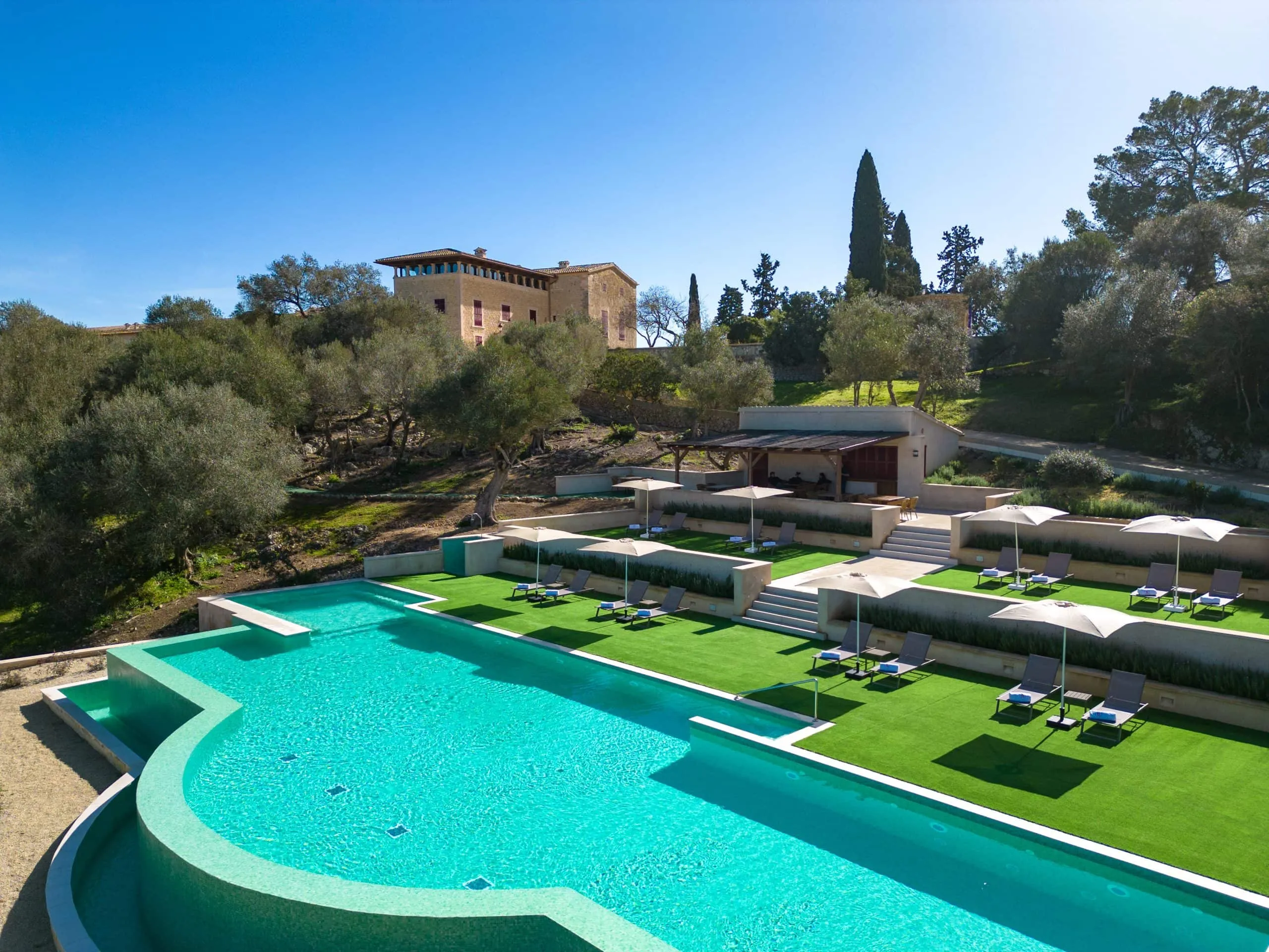 Piscina exterior en terrazas del hotel Finca Sa Bastida con tumbonas y la finca al fondo, Sant Joan