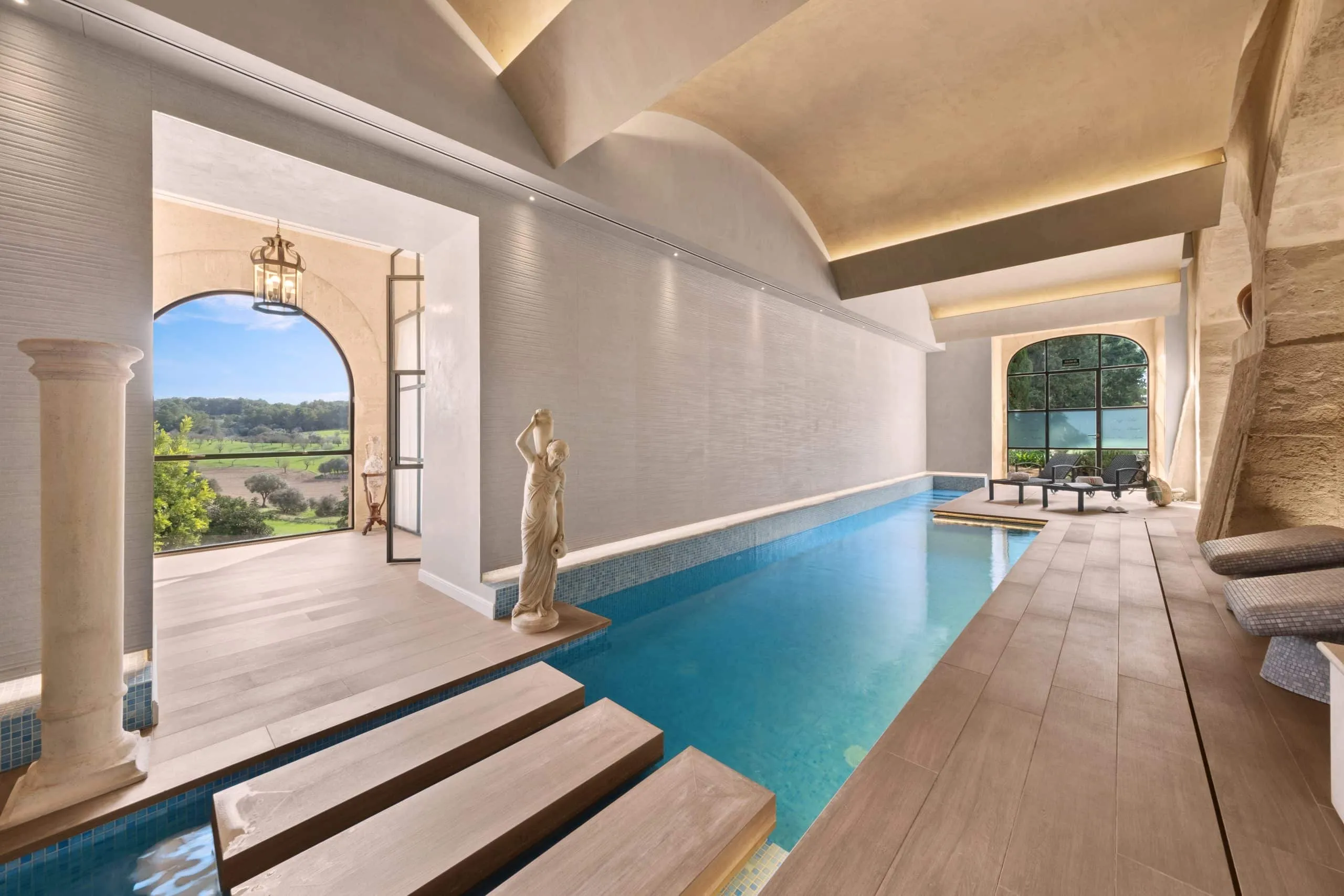 Piscina interior del spa del hotel Sa Bastida con arcos de piedra y escultura, Sant Joan, Mallorca