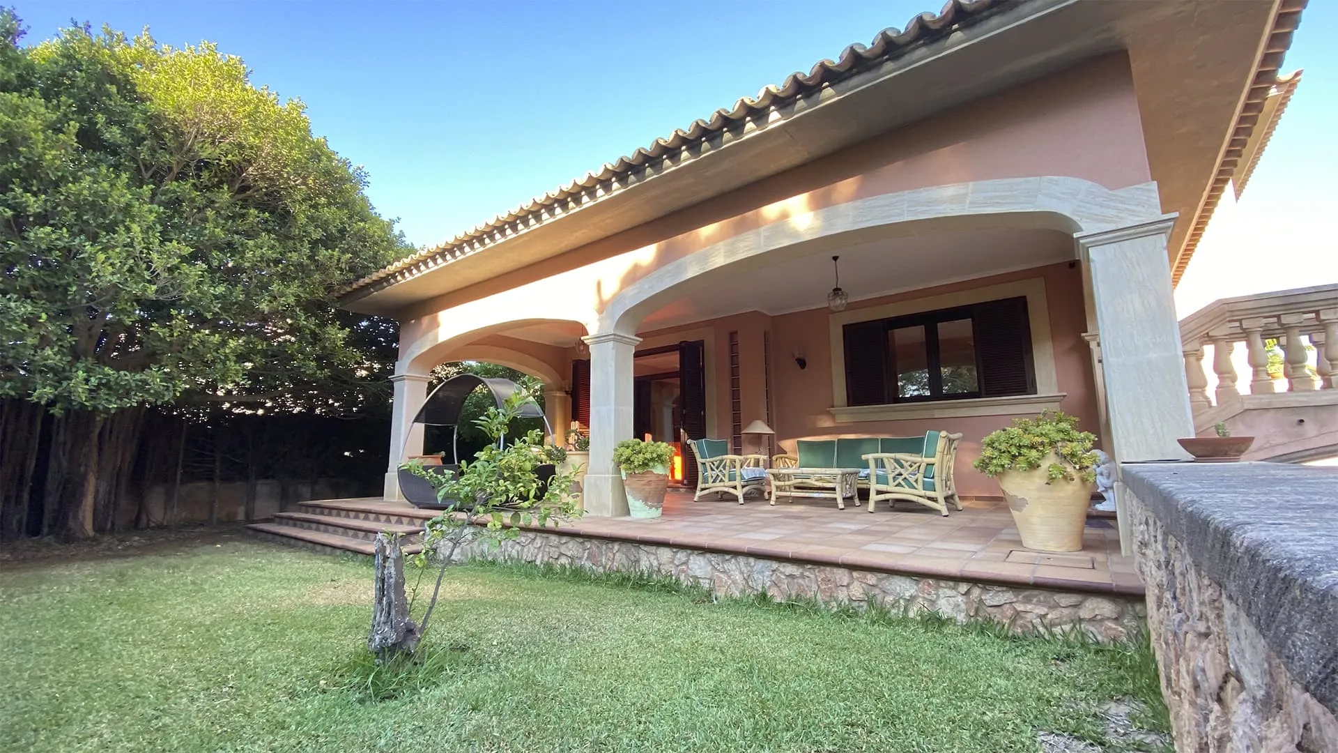 Porche cubierto con arcos y mobiliario de jardín frente al césped, vivienda Xiela, Bunyola