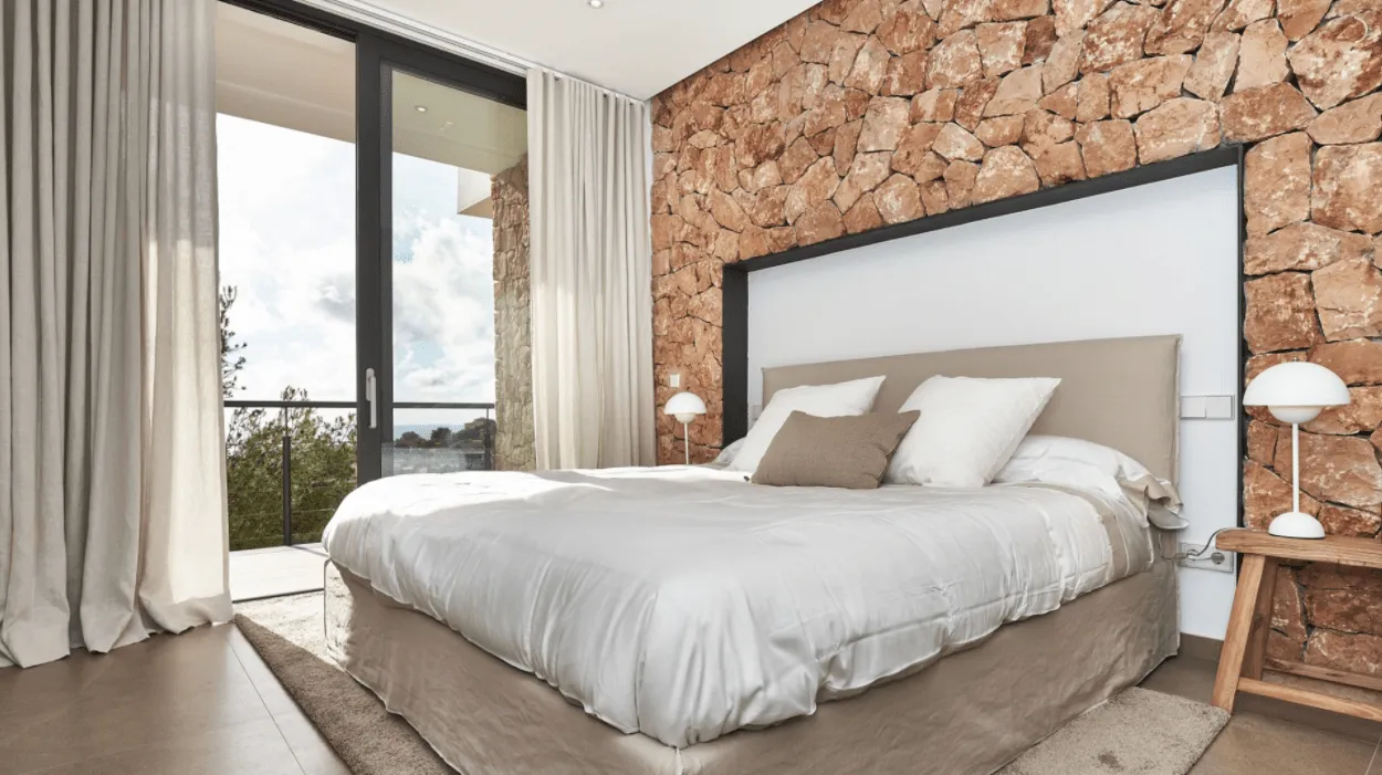Dormitorio con cabecero y muro de piedra en la vivienda Génova de Palma de Mallorca