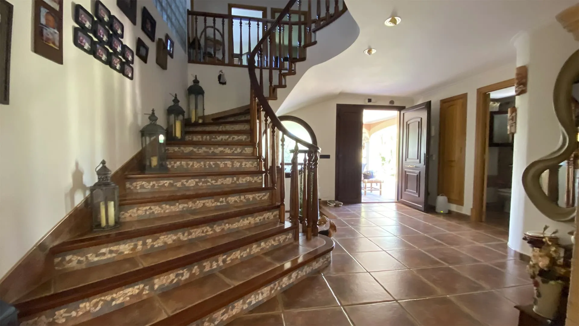 Recibidor con escalera de madera curvada y peldaños decorados en la vivienda Xiela, Bunyola