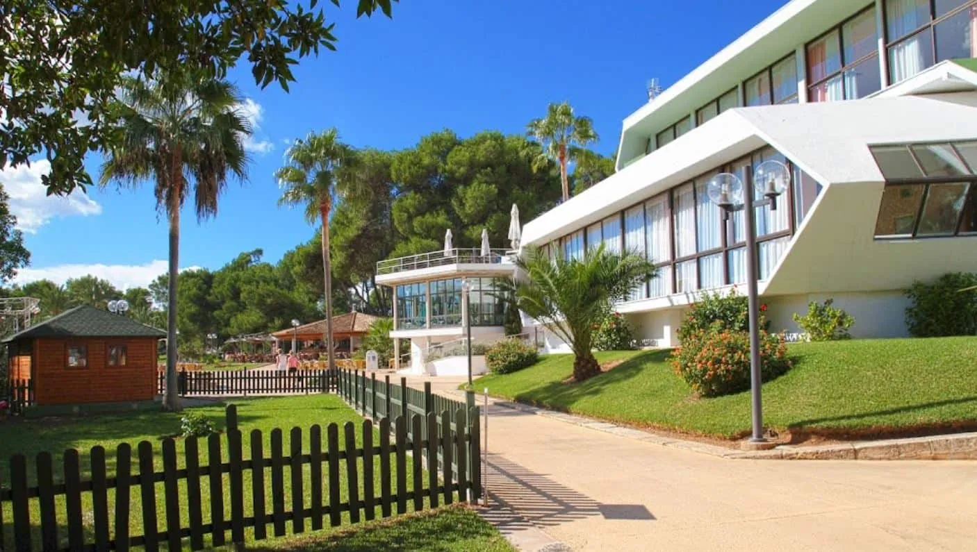 Cuerpo de acceso del Hotel Exagon Park con jardín y vegetación