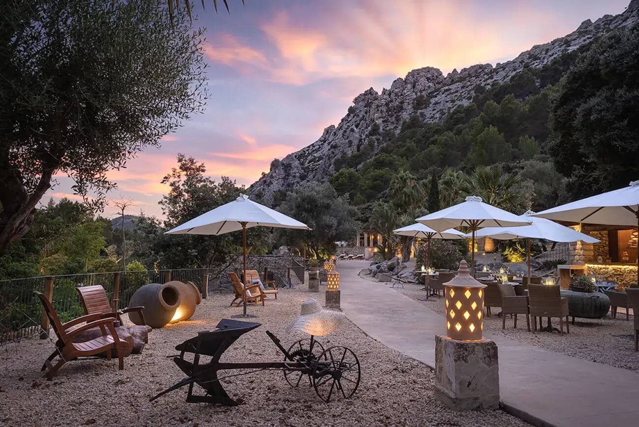 Terraza al atardecer en el hotel Es Ratxó con sombrillas y arados antiguos