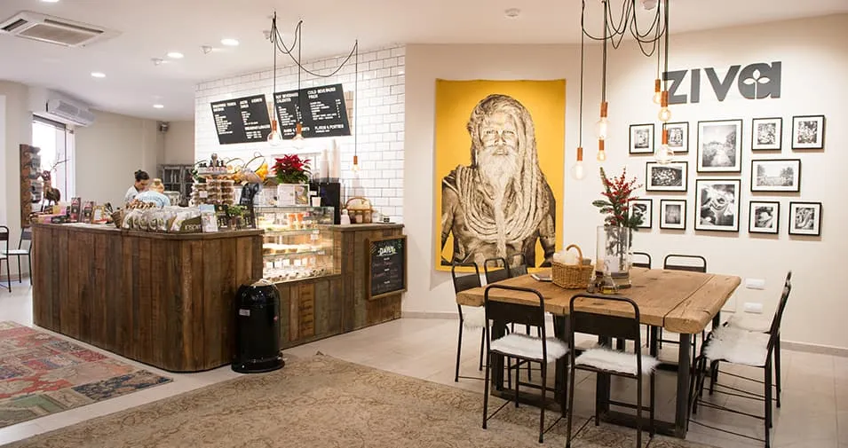 Interior de la cafetería Ziva en Palma con barra, mesa y pared de fotos