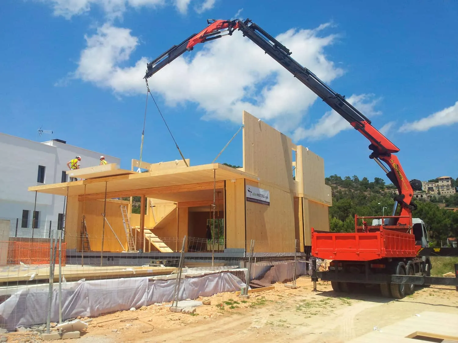 Grúa izando un panel de madera en la obra de la vivienda ADG en Palma