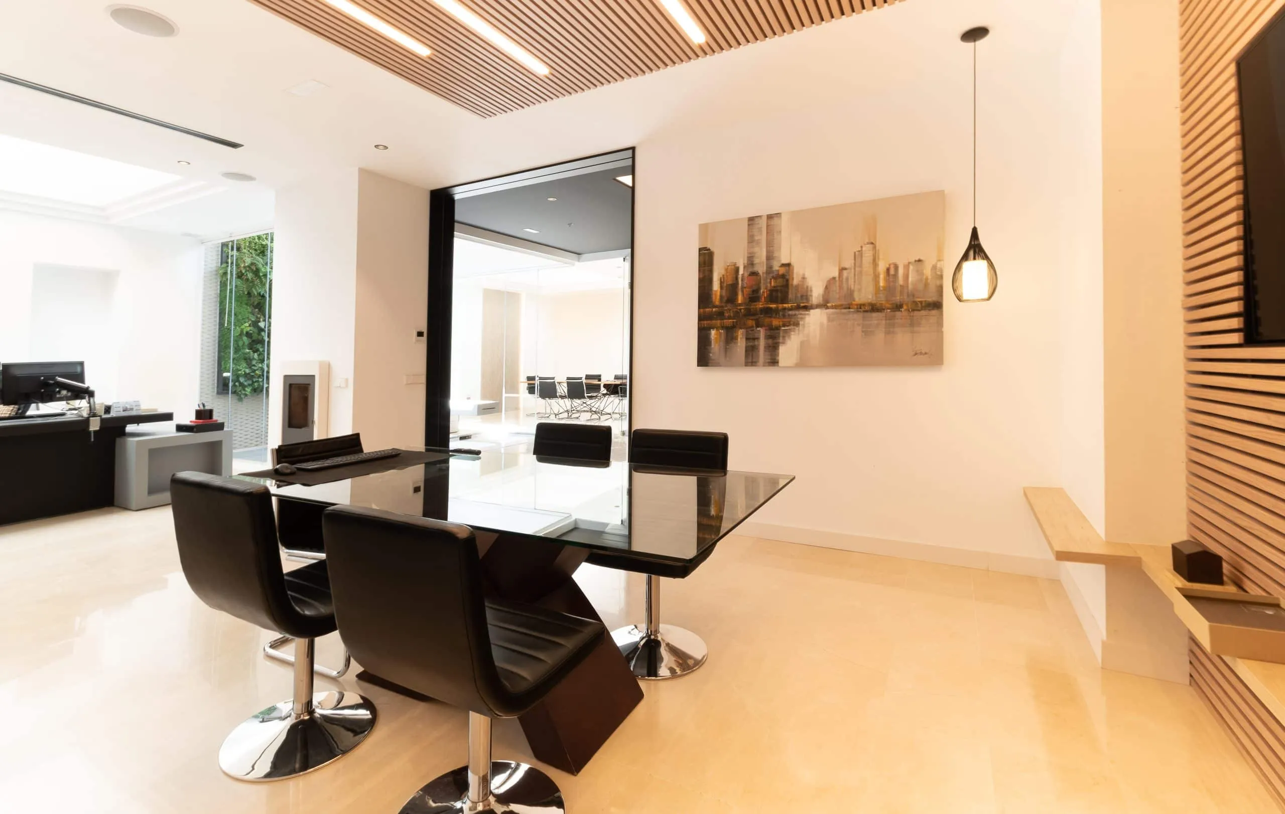Mesa de despacho de cristal con sillas negras en la oficina HOMEY de Palma de Mallorca