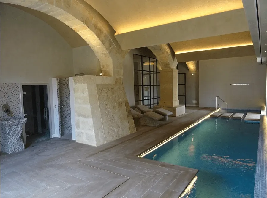 Piscina interior del spa del hotel Sa Bastida con bóvedas de piedra y zona de reposo, Mallorca