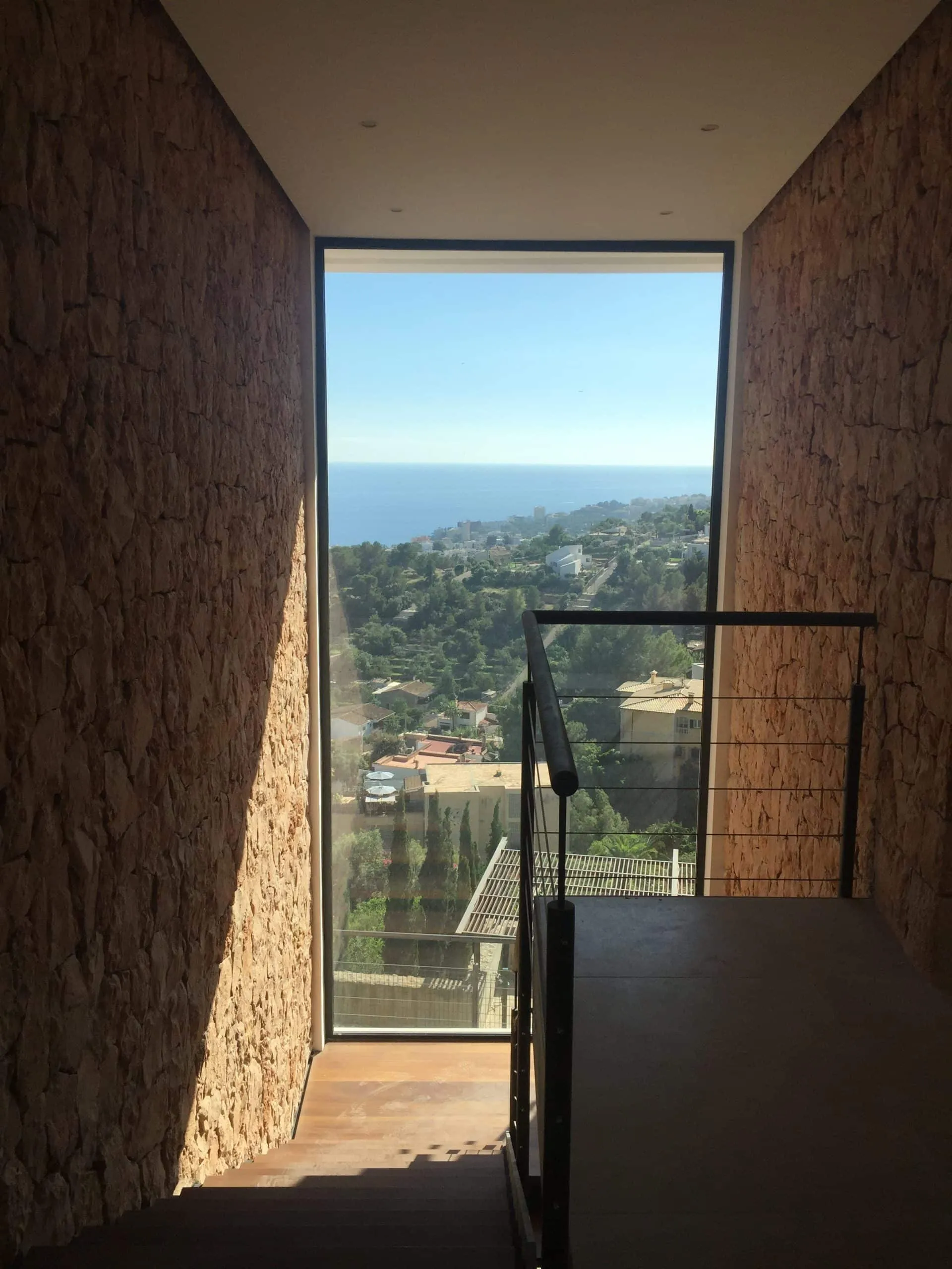 Mirador vertical con ventana al mar entre muros de piedra en la vivienda Génova, Palma