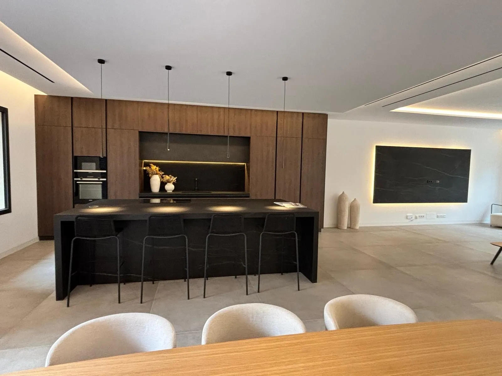 Cocina construida con isla negra y taburetes en la vivienda Avenidas de Palma