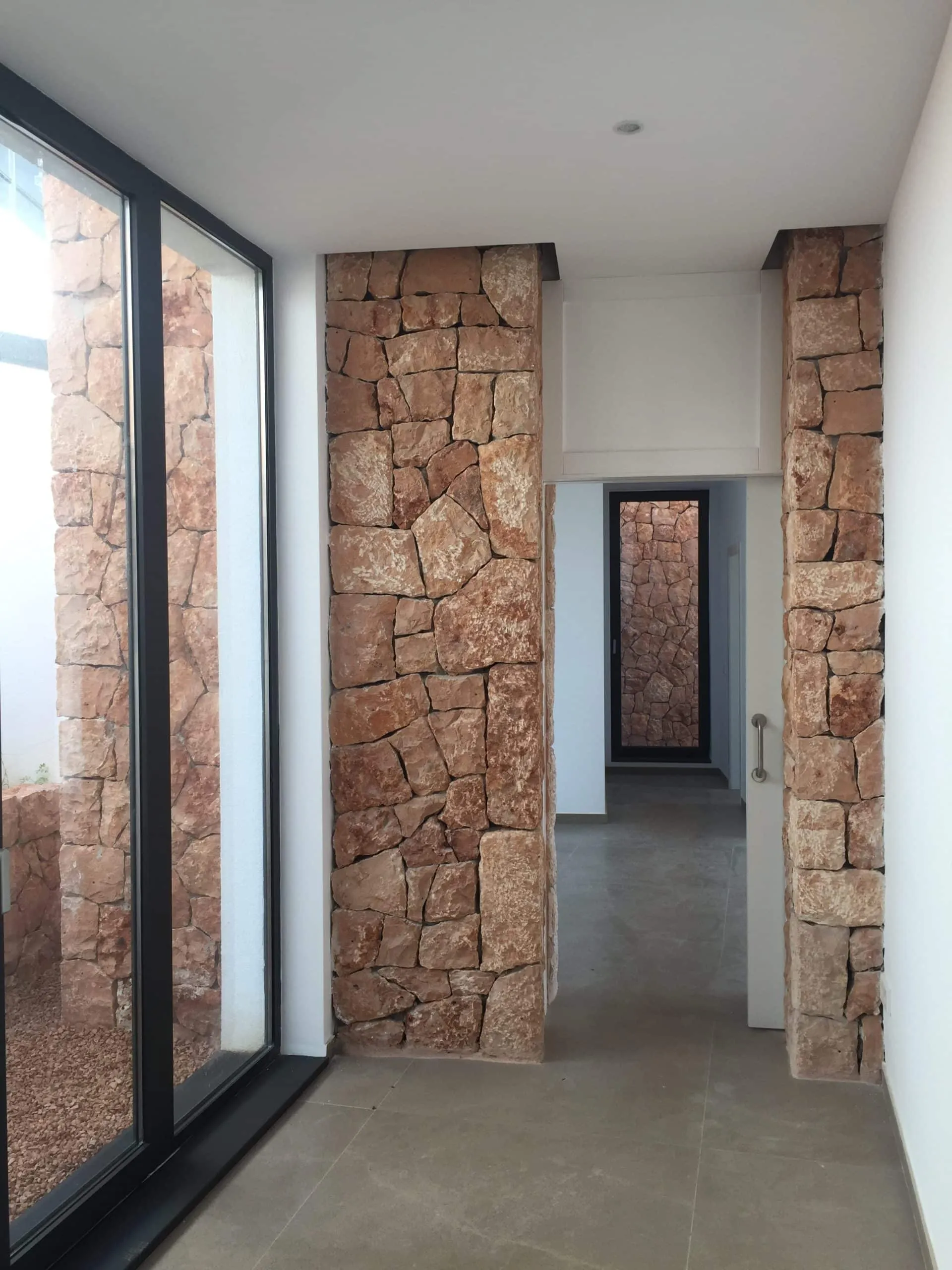 Pasillo acristalado con pilares de piedra en la vivienda Génova de Palma de Mallorca
