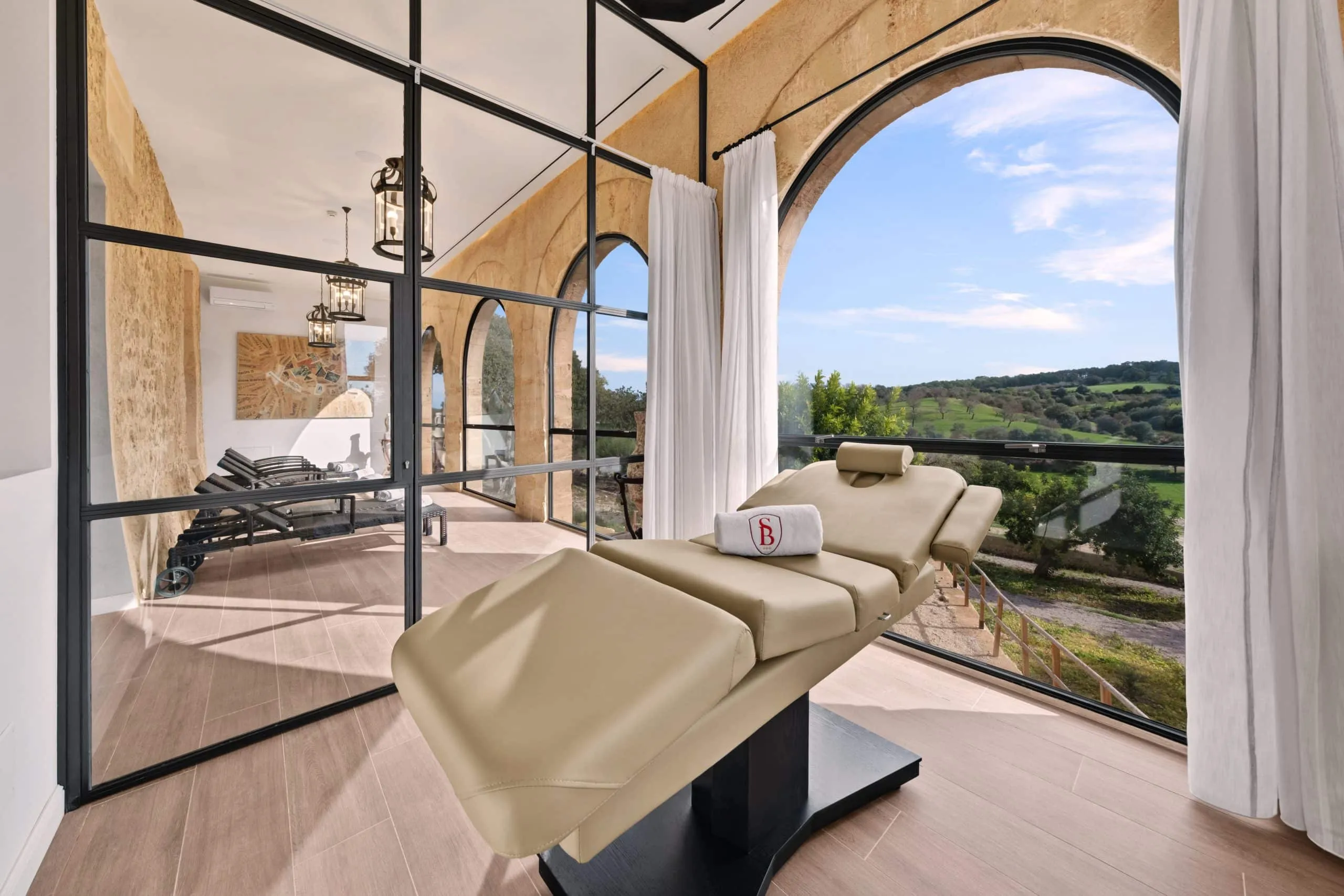 Cabina de tratamiento del spa de Sa Bastida con ventanal en arco y vistas al campo, Mallorca