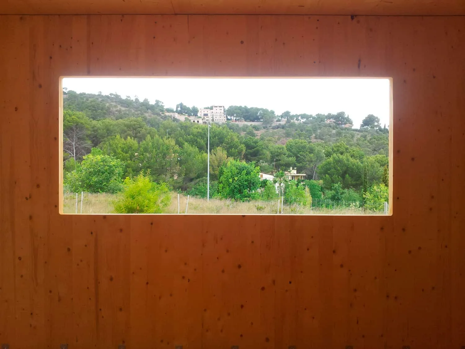 Vista desde el interior de ADG por una ventana abierta en un muro de madera