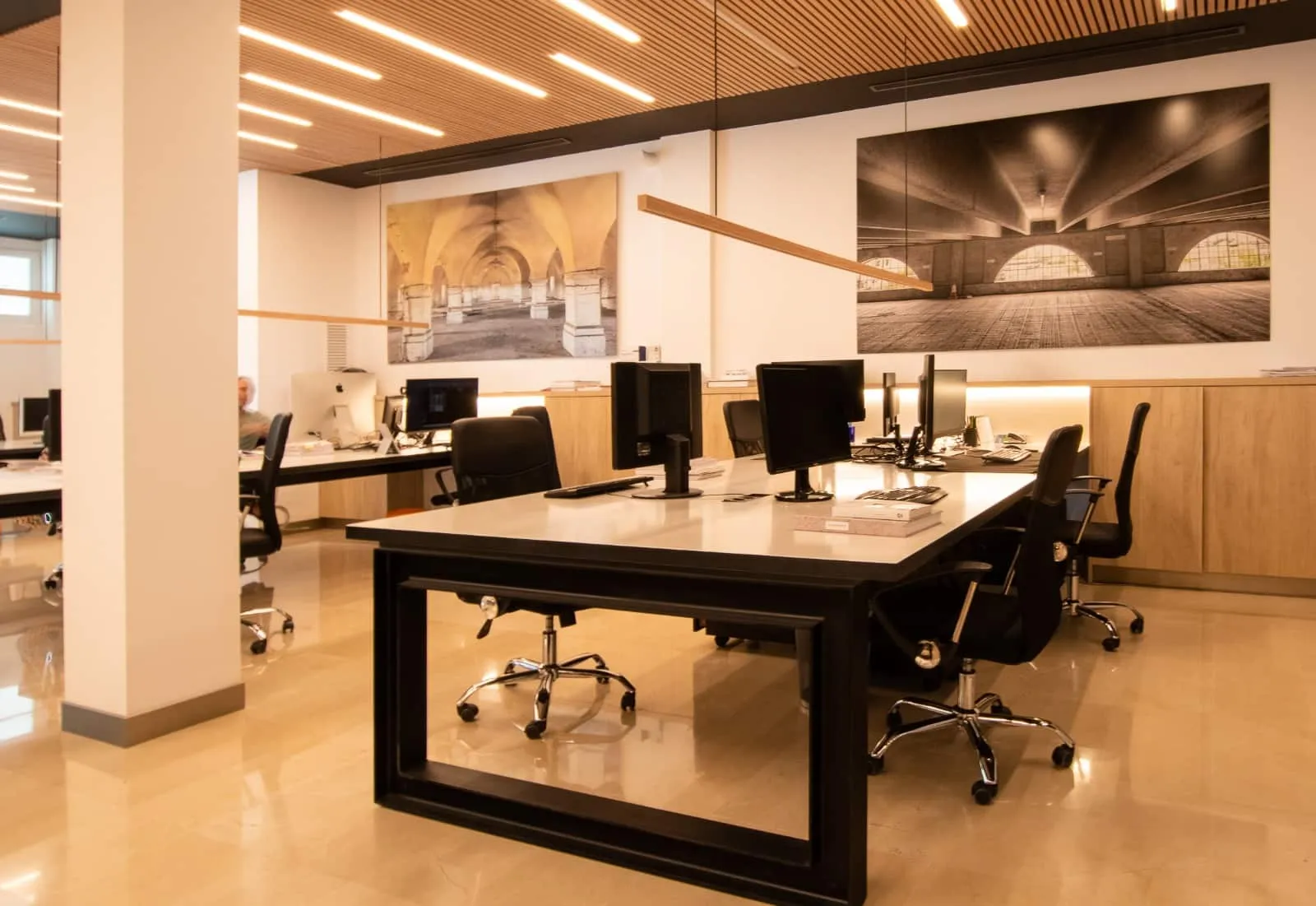 Puestos de trabajo con mesas corridas de estructura negra en la oficina HOMEY, Palma
