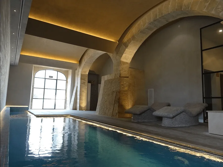 Piscina cubierta del spa de Sa Bastida con arcos de piedra e iluminación indirecta, Sant Joan
