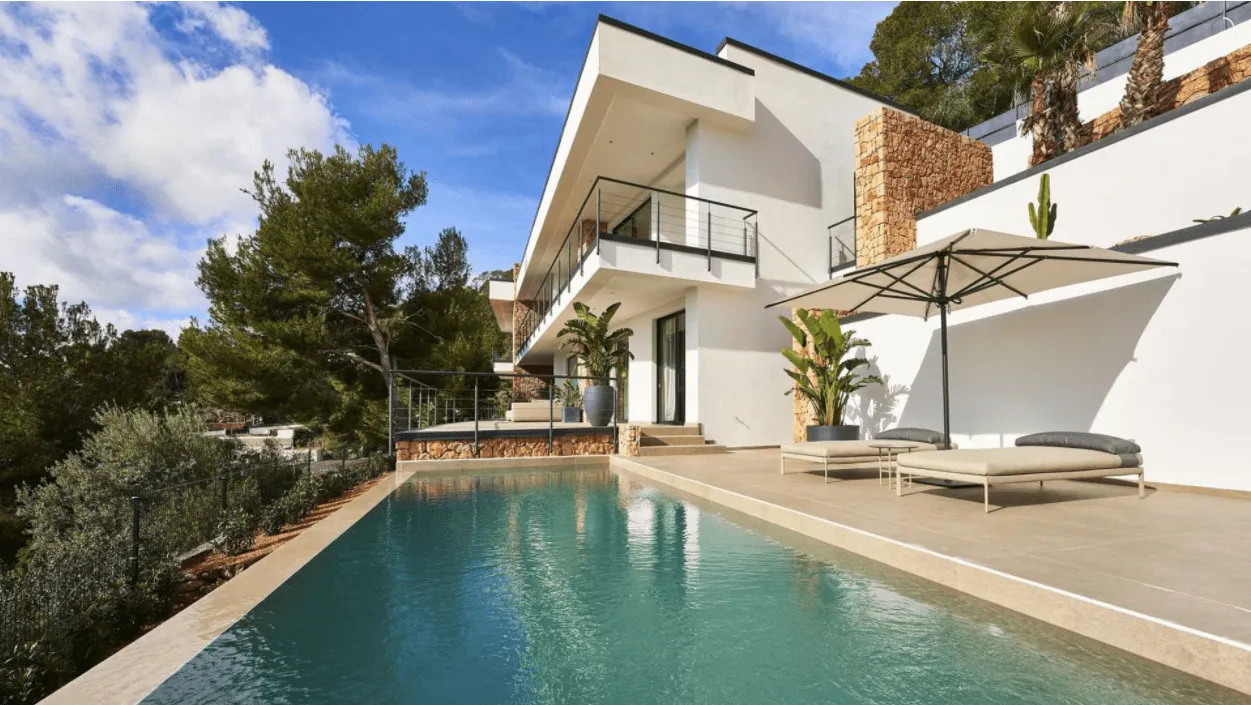 Piscina y fachada principal de la vivienda Hoff en Palma, con sombrilla