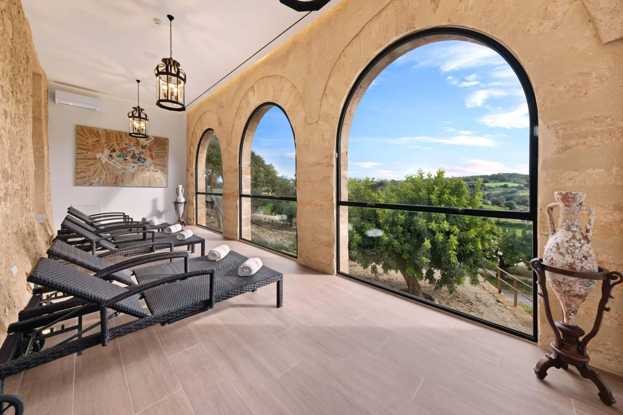 Zona de relax del spa del hotel Sa Bastida con tumbonas frente a arcos con vistas, Sant Joan