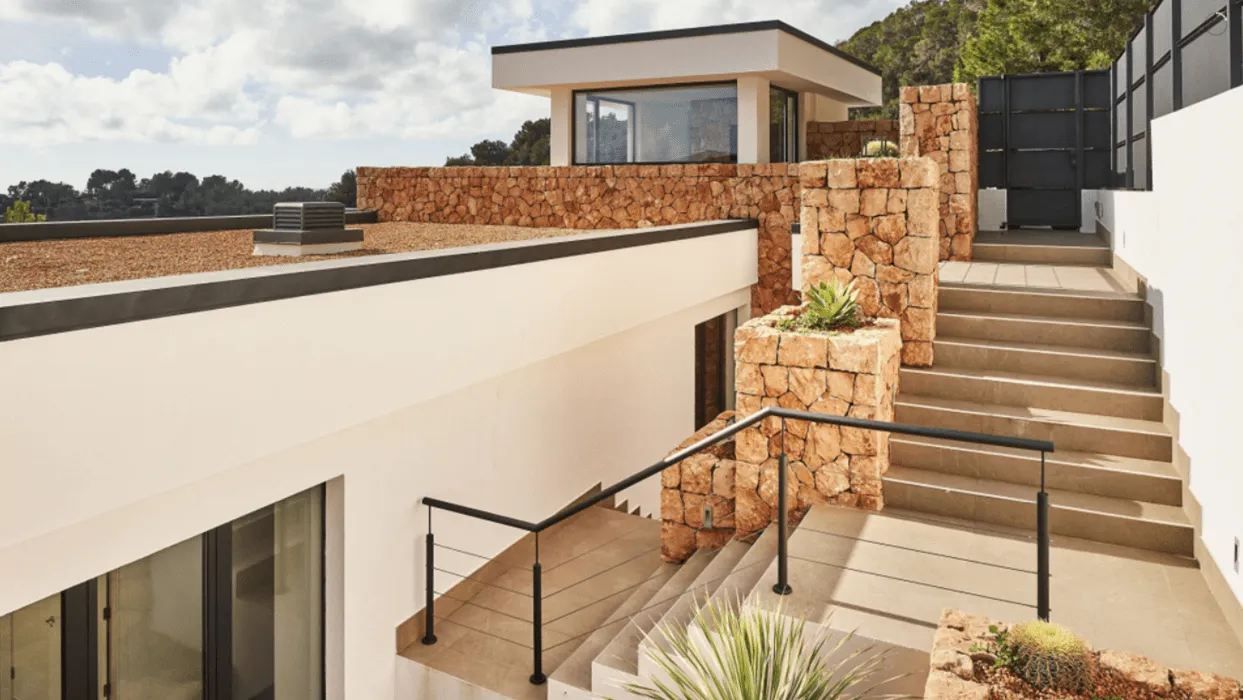 Escaleras exteriores y cubierta de la vivienda Hoff entre muros de piedra