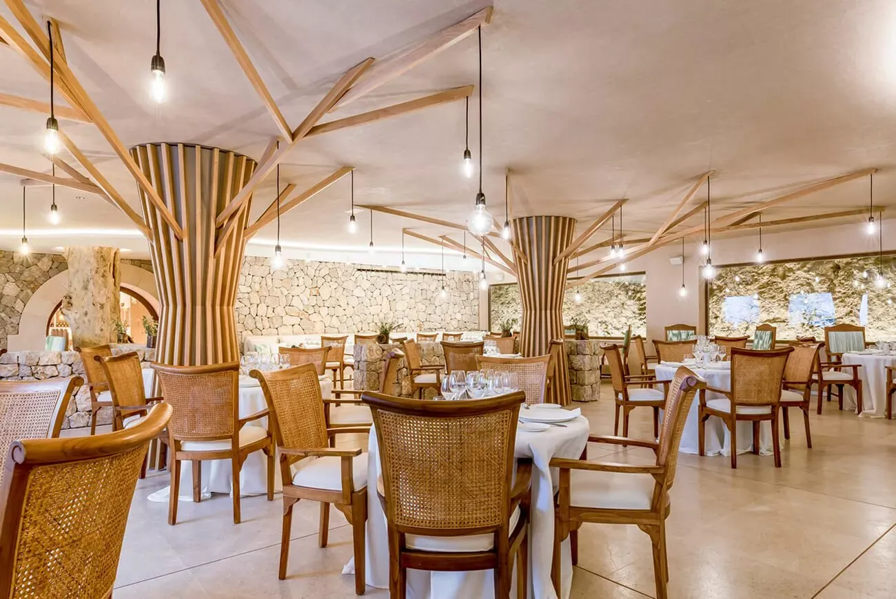 Restaurante del hotel Es Ratxó con columnas de madera y muros de piedra