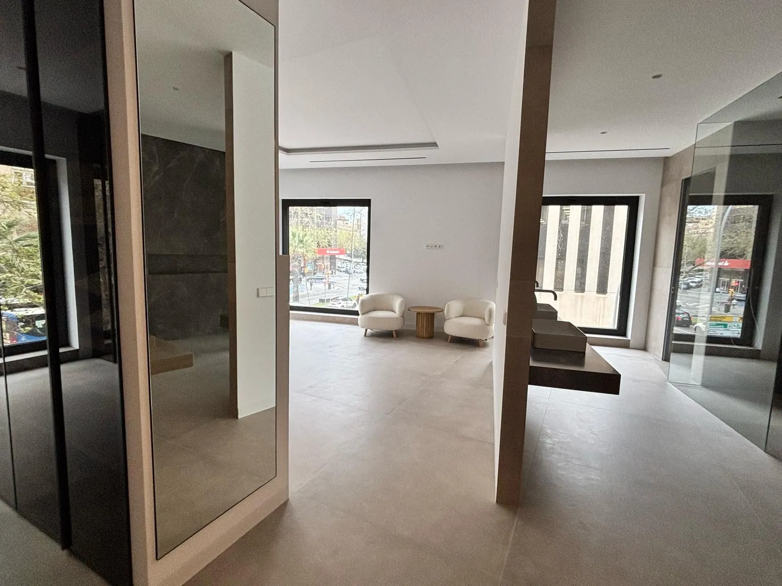 Sala con pilar, espejo y vistas a la avenida a través de ventanales en la vivienda Avenidas