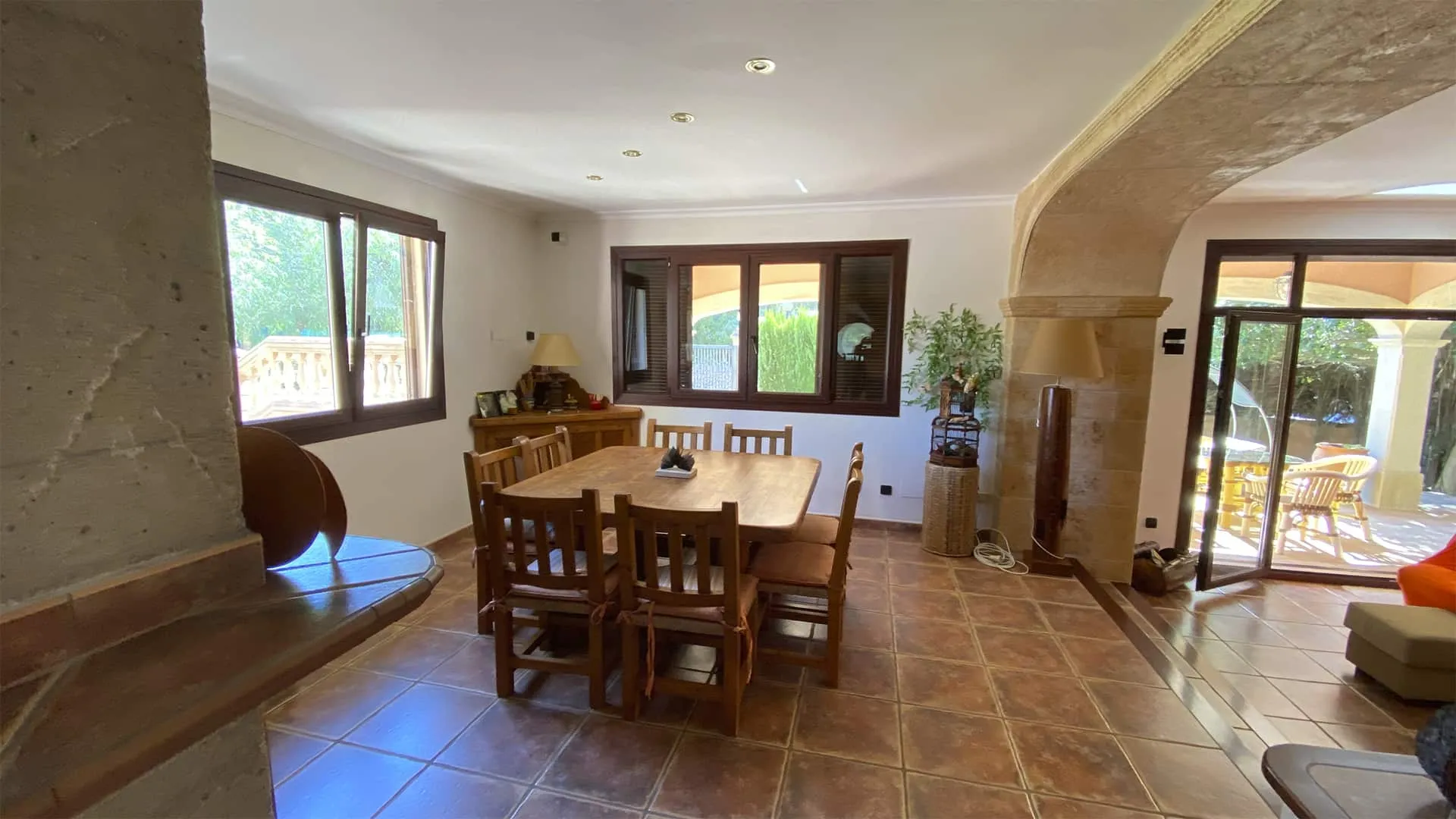Comedor y salón con arco de piedra y ventanal al jardín en la vivienda Xiela de Bunyola