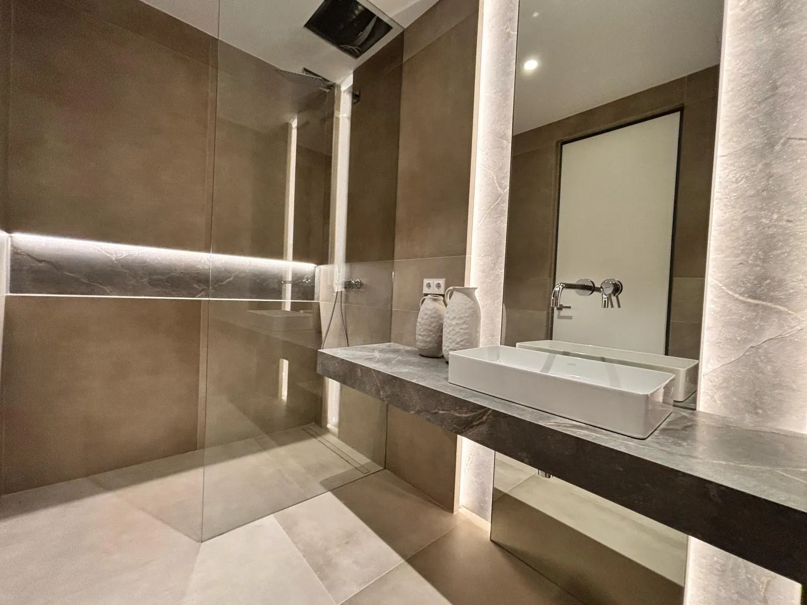 Baño con lavabo sobre piedra, ducha y luz perimetral en la vivienda Avenidas de Palma