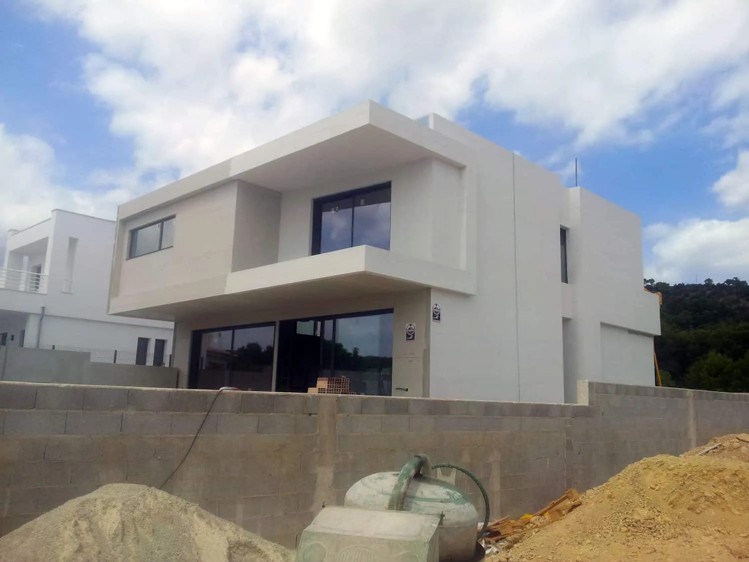 Fachada de ADG en Palma con acabado blanco, terraza volada y obra en el jardín