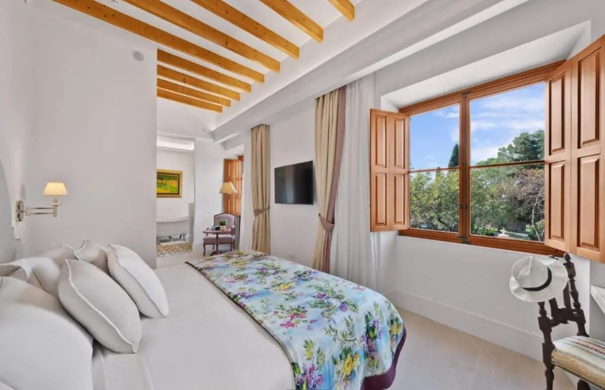 Habitación del hotel Finca Sa Bastida con vigas de madera vistas y contraventanas, Mallorca