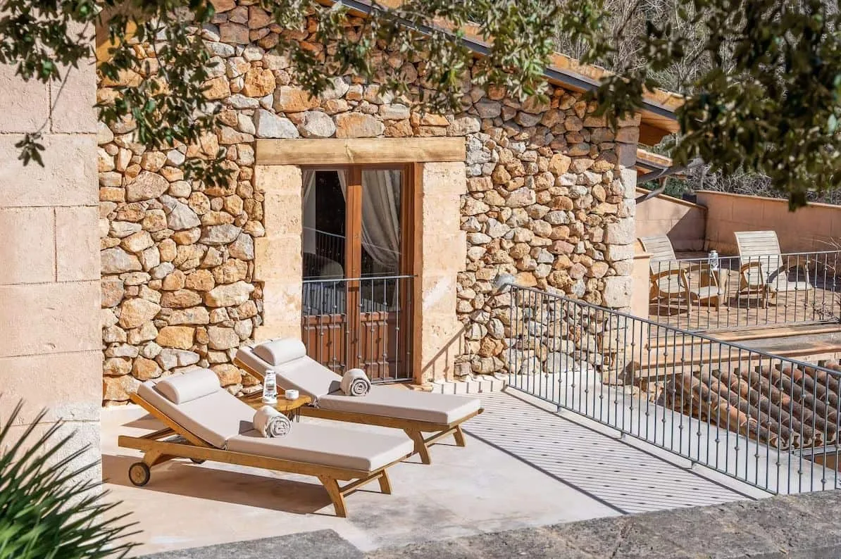 Terraza con tumbonas ante una puerta de madera, hotel Es Ratxó, Puigpunyent