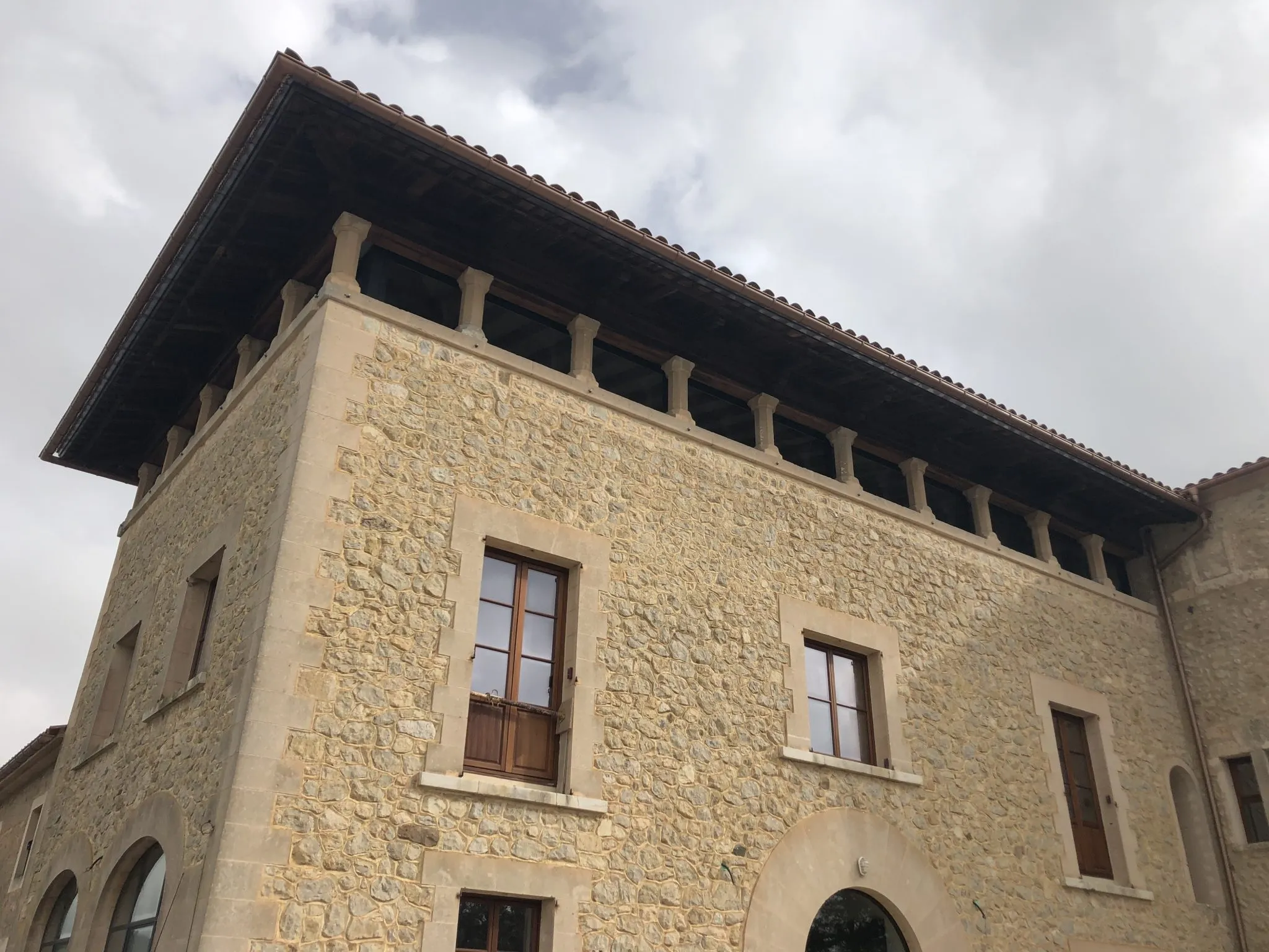 Fachada de piedra de Sa Bastida con esquinas de marés, ventanas de madera y galería bajo el alero