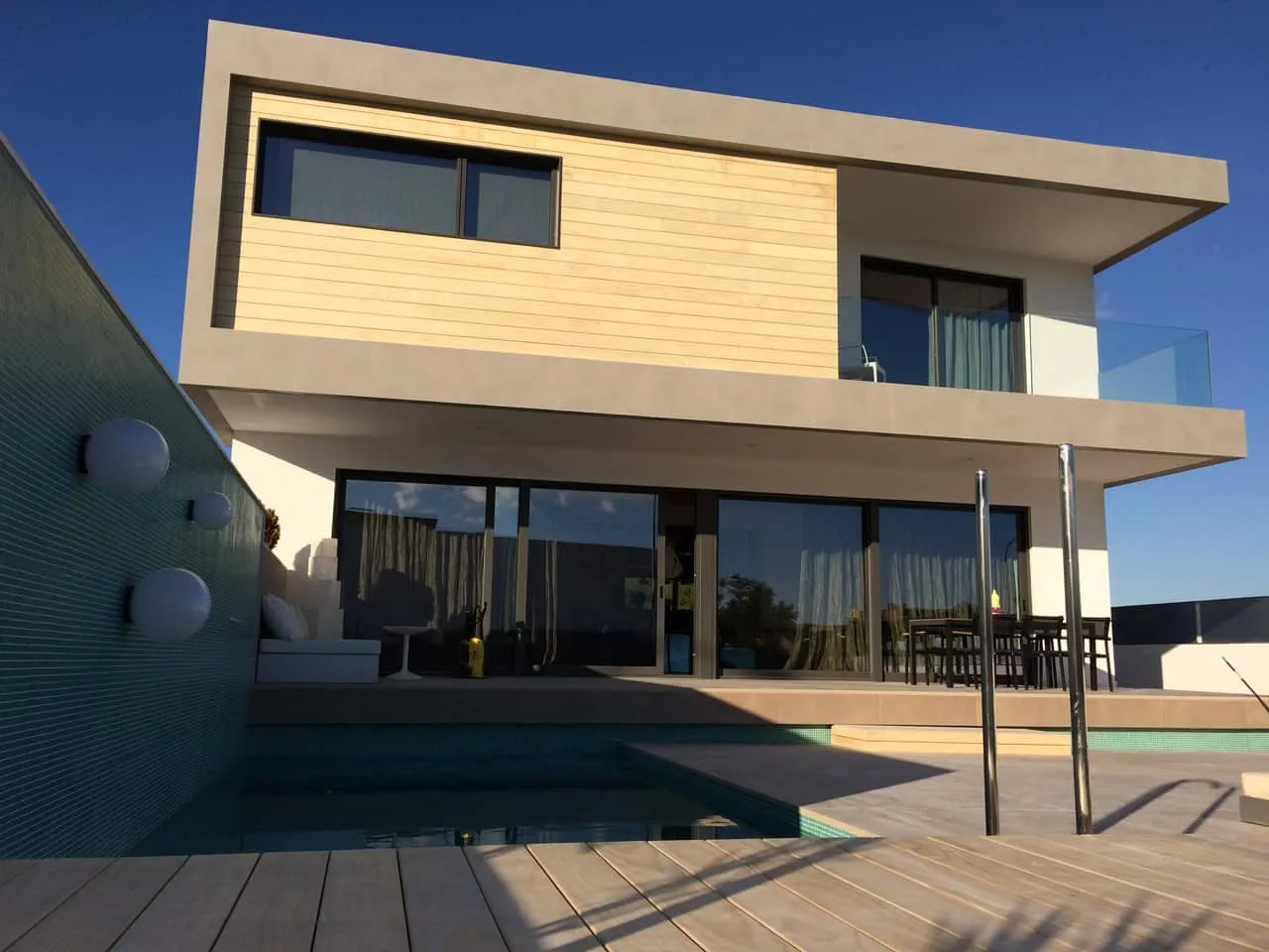 Fachada de ADG con piscina, terraza de madera y revestimiento de madera clara