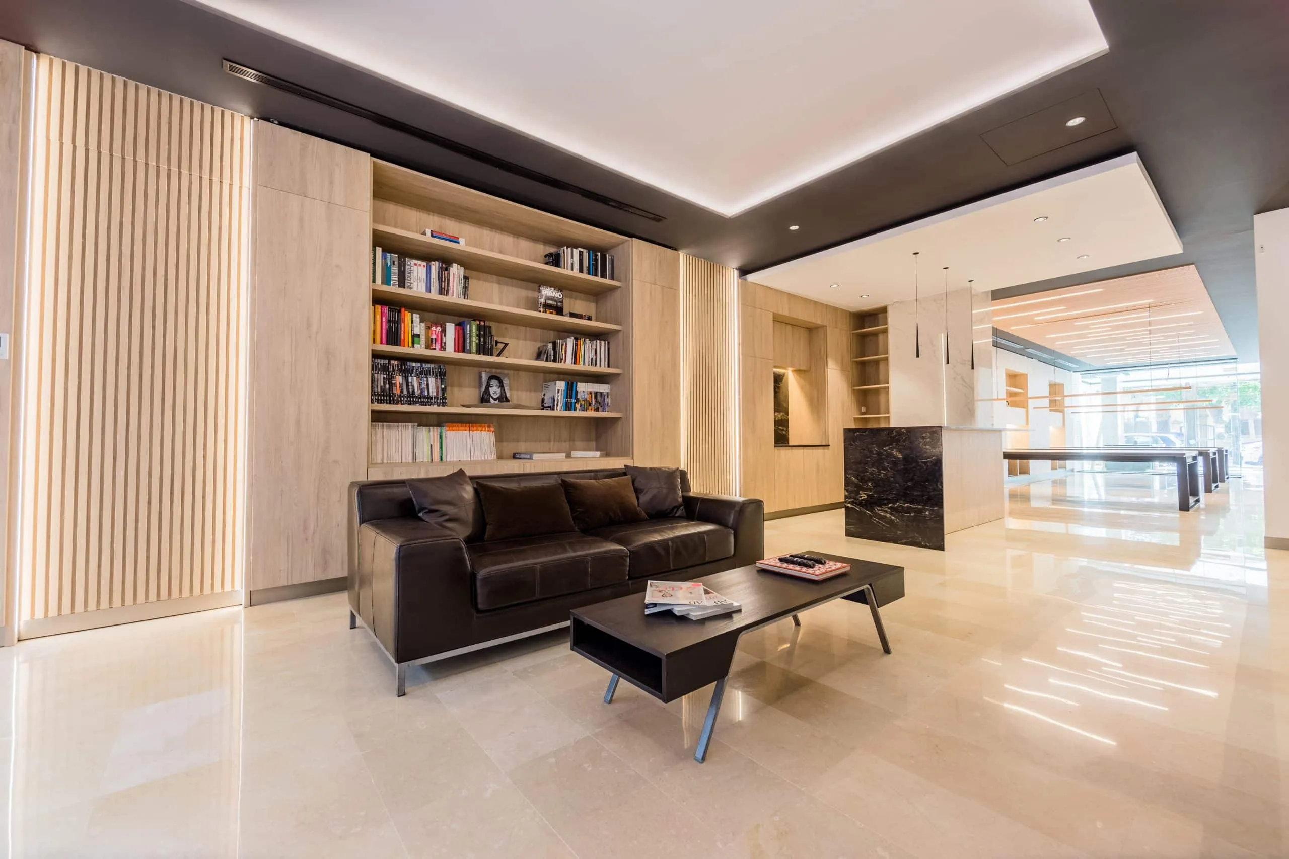 Zona de estar con sofás y estanterías de madera en la oficina HOMEY, Palma de Mallorca